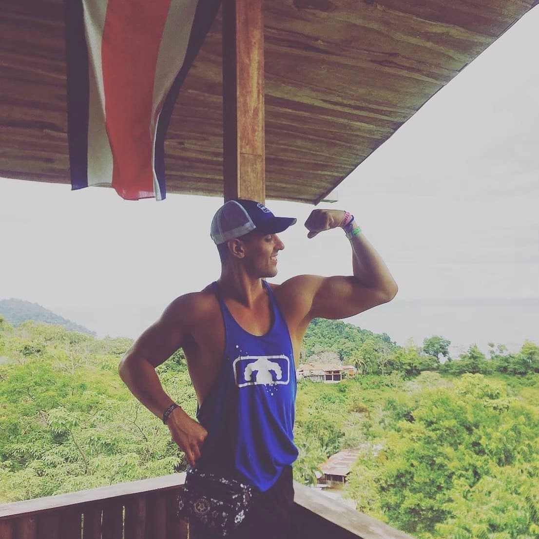Ty flexing his arm on a balcony above the treeline