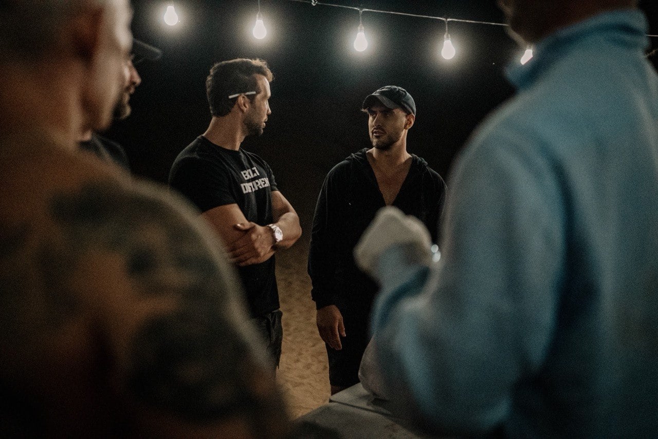 Ty in conversation with another man under string lights at night