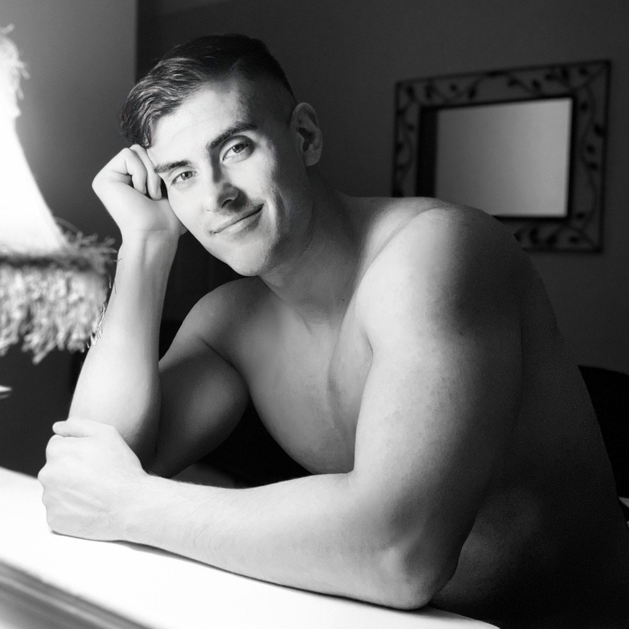 Black and white portrait of Ty leaning on a counter indoors